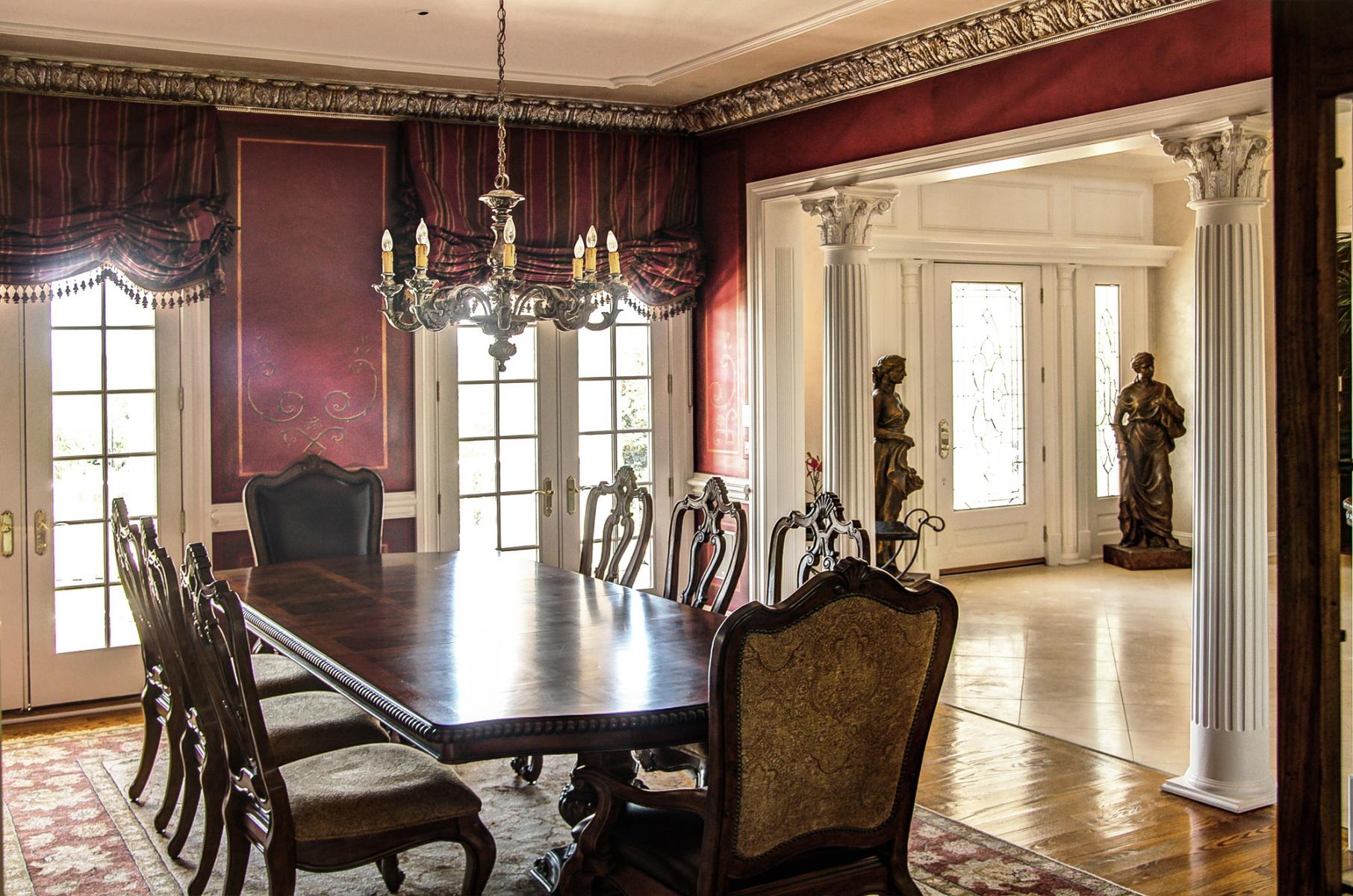 Stencil designs over wine colored walls with a faux metal plaster cornice and chandelier topped with an accented ceiling. Stunning!