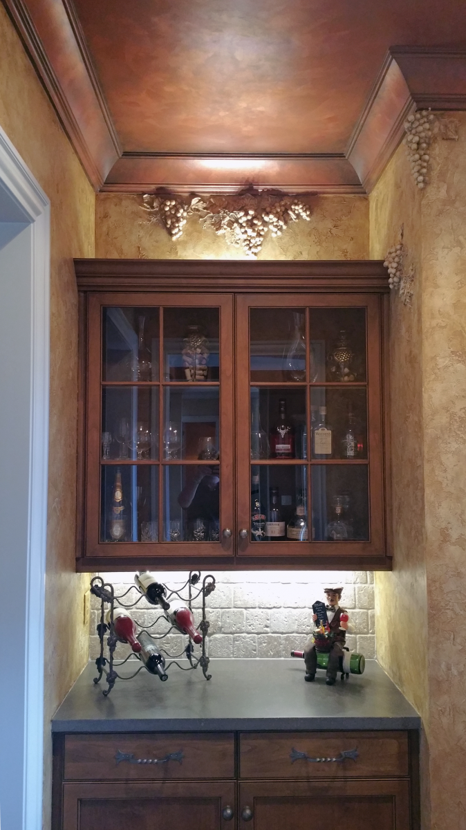 Brentwood customer’s butler’s pantry converted into a stunning Bourbon and wine room with Tuscan plaster walls sculpted grapes motifs and faux copper ceiling.
