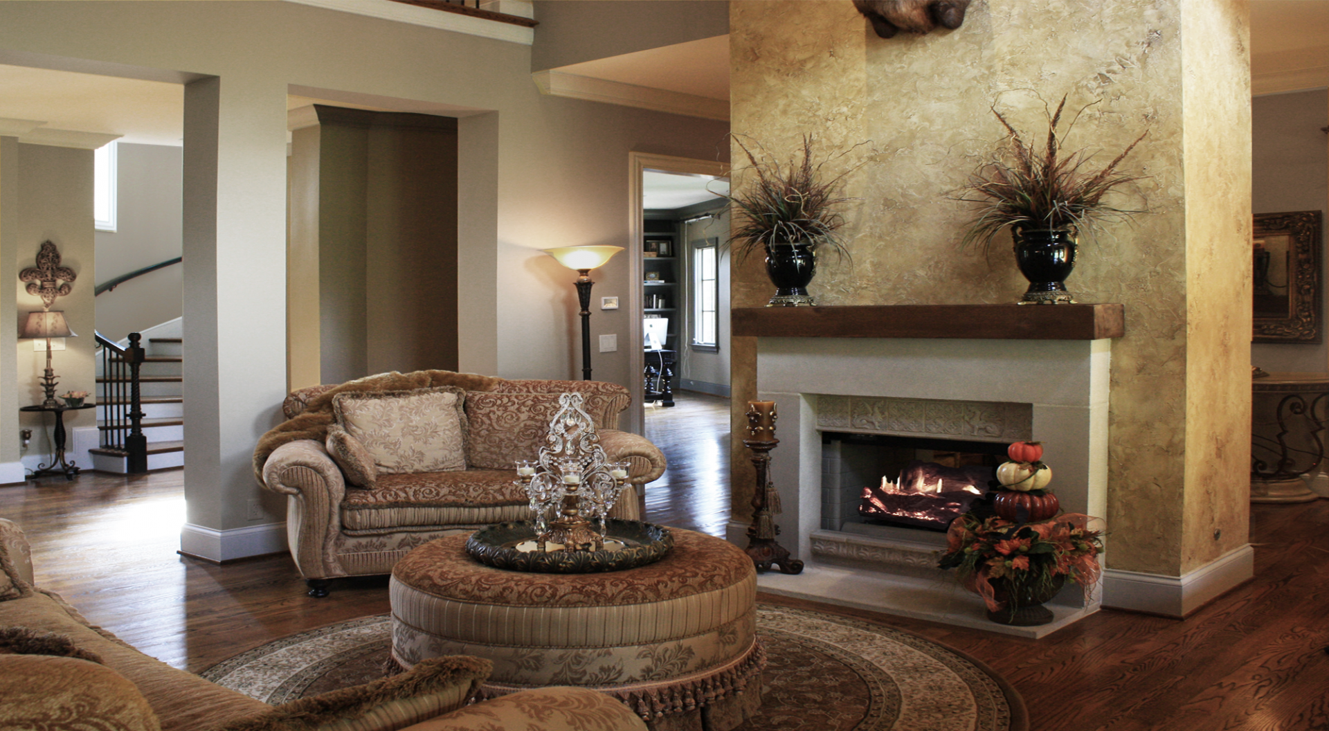 Custom great room wall color with a rustic faux plaster feature wall and faux wood ceiling beams.