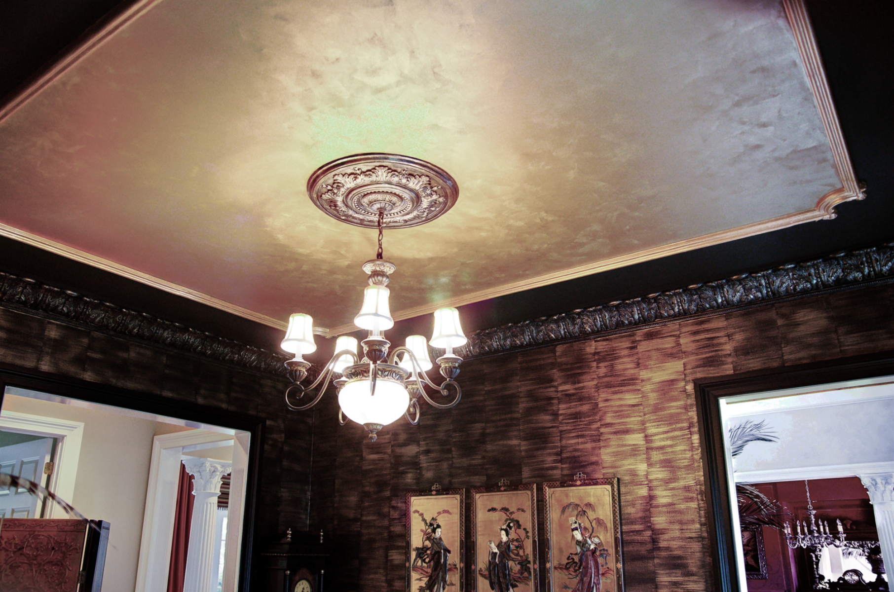 Black woodwork with gold faux bamboo walls and faux metal plaster cornice above.