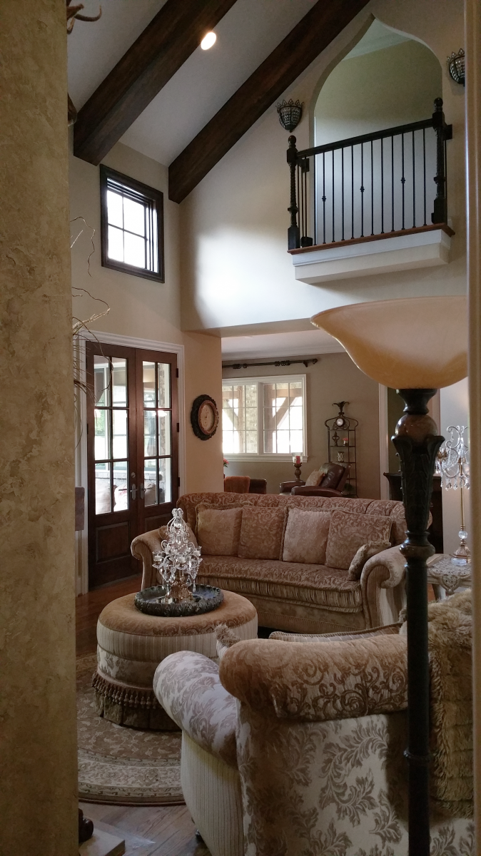 Custom great room wall color with a rustic faux plaster feature wall and faux wood ceiling beams.